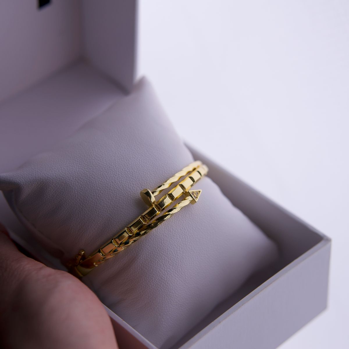 Pulseira dourada apresentada em caixa de presente aberta